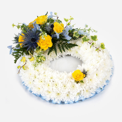 Wreath SYM-319 - White Massed Wreath with Blue & Yellow Spray. 
